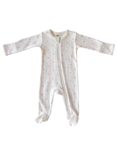 White baby onesie with pink hearts, long sleeves and footed design, featuring a front zipper closure.