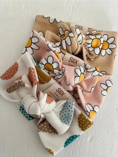 Three colorful fabric headbands with floral and polka dot patterns stacked on a white surface.