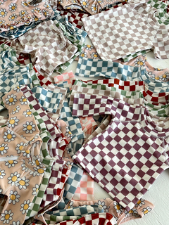 Colorful patterned children's clothing, featuring floral and checkered designs, arranged in a neat pile.