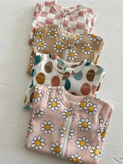 Four children's zippered pajamas featuring floral and patterned designs stacked neatly on a light surface.