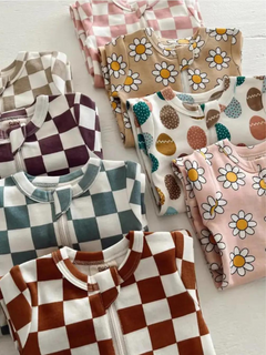 Assorted baby bodysuits in pastel colors, featuring floral and checked patterns, neatly folded on a flat surface.