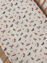 Patterned fabric featuring colorful, whimsical illustrations of various birds on a light background.