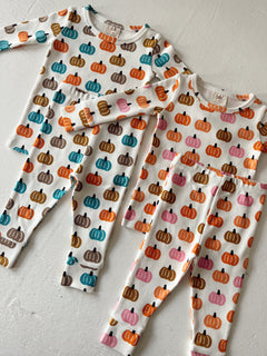Three pairs of children's pajamas with colorful pumpkin patterns on a white background.
