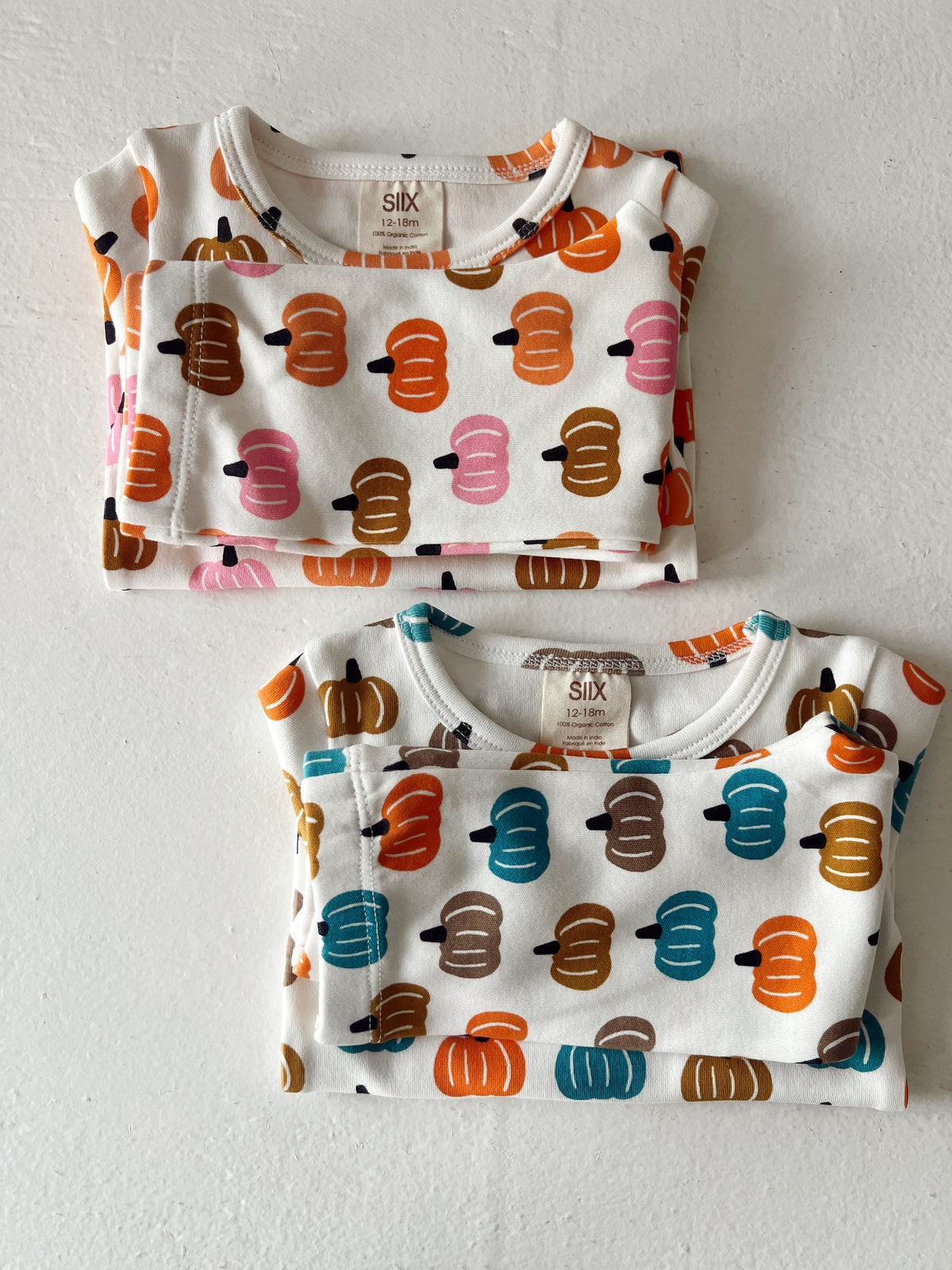 Two folded toddler shirts featuring colorful pumpkin patterns on a white background, sizes 12-18 months.