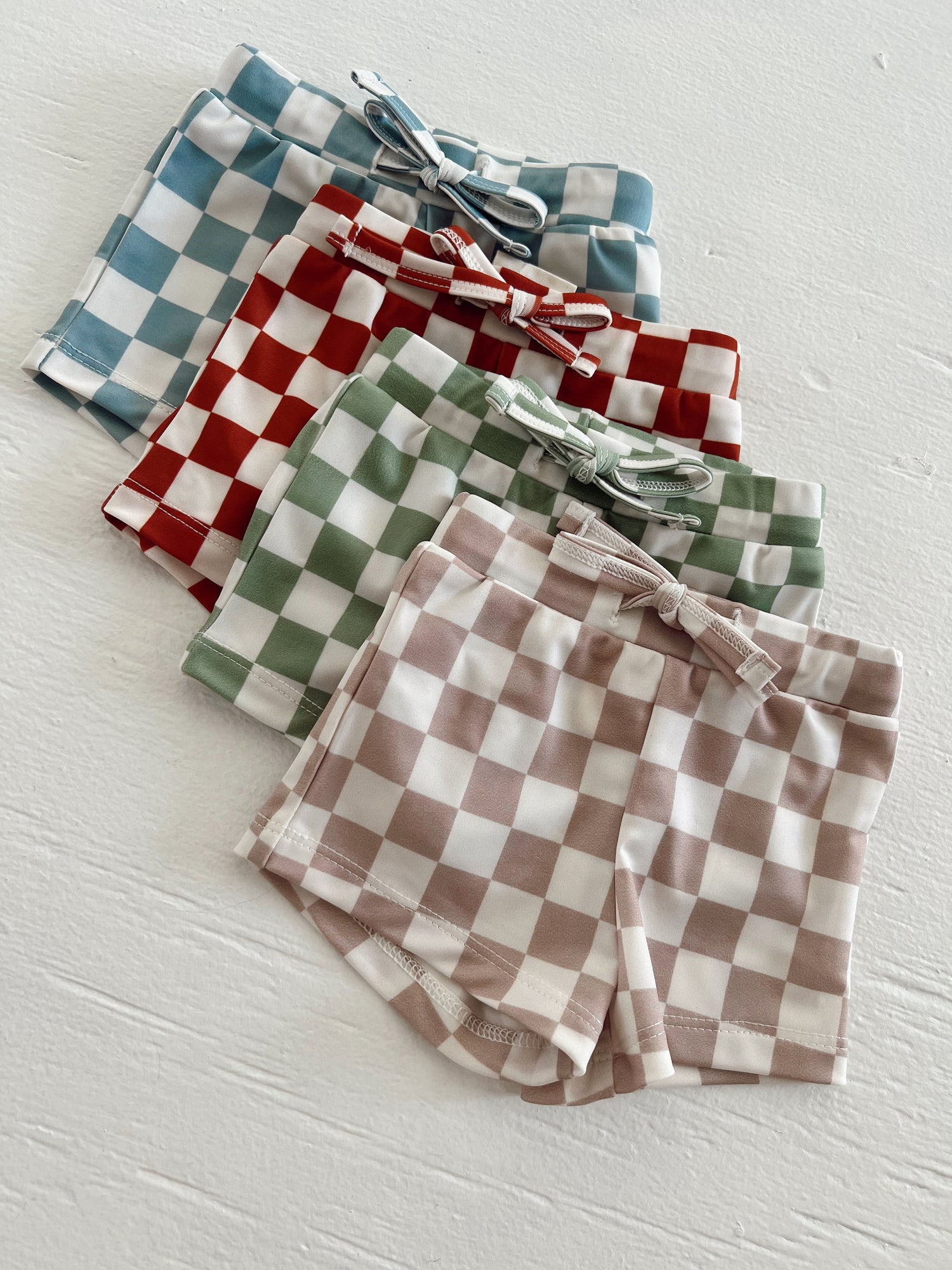 Colorful checkered shorts in blue, red, green, and beige arranged neatly on a white background.
