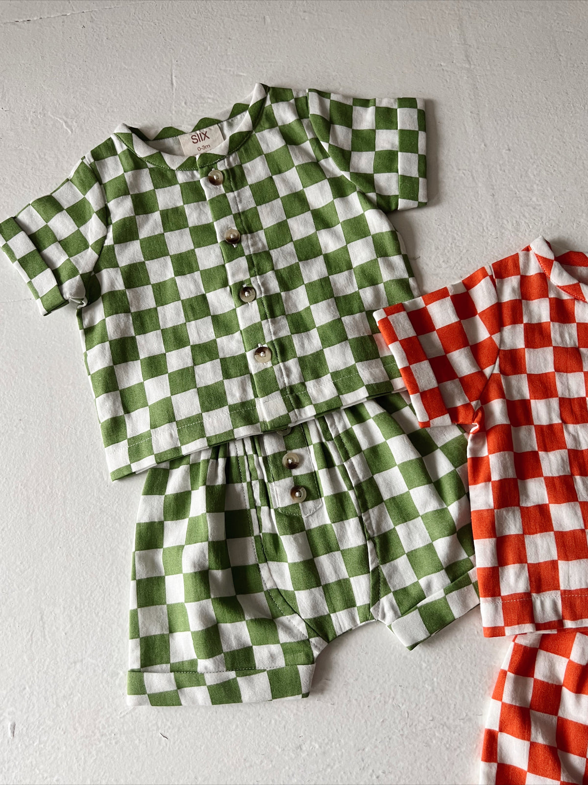 Child's checkered outfit in green and white with matching shorts; includes a red and white checked set.