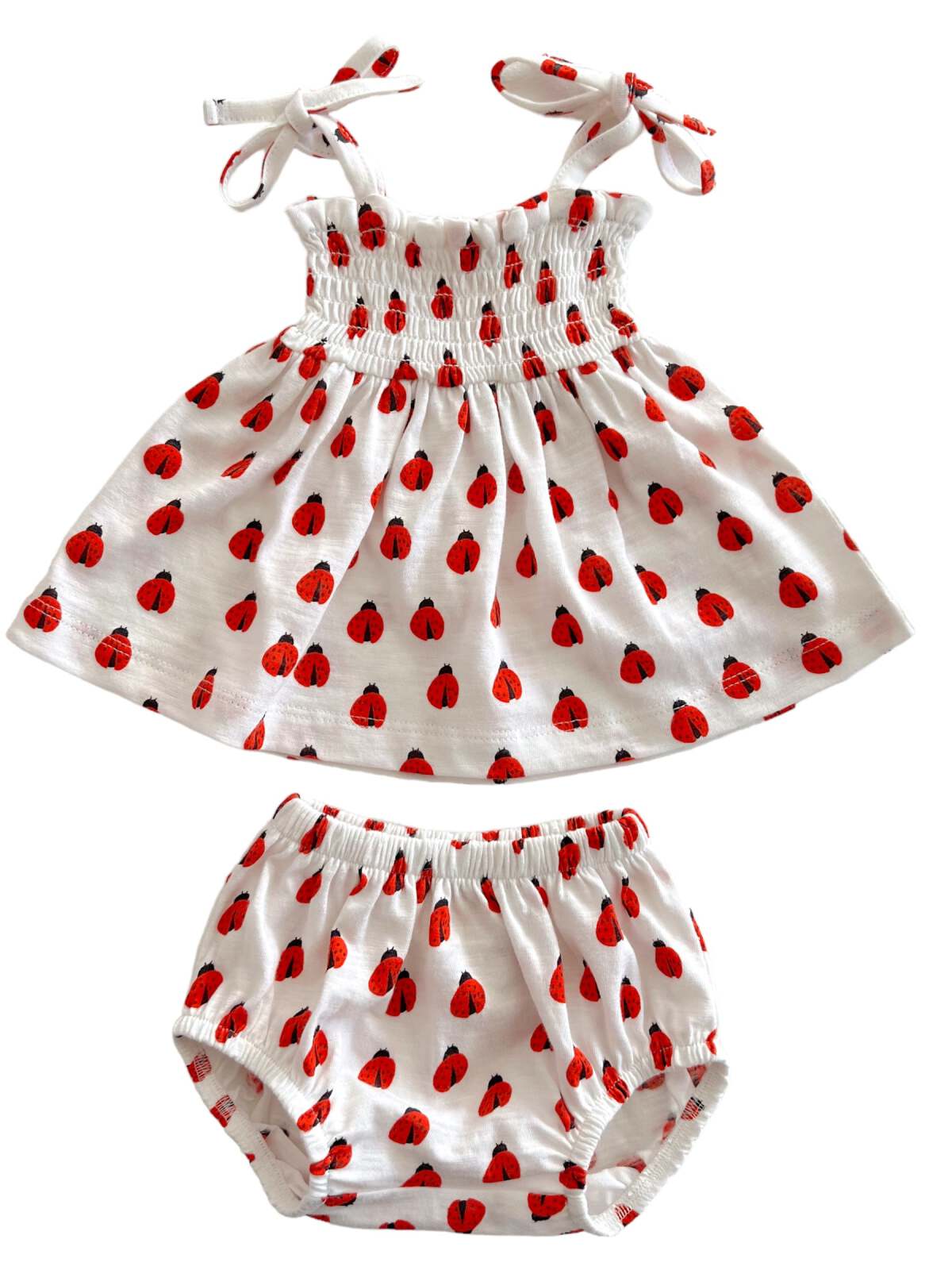 White dress and matching bloomer set with red ladybug prints and tie straps. Perfect for warm-weather outings.