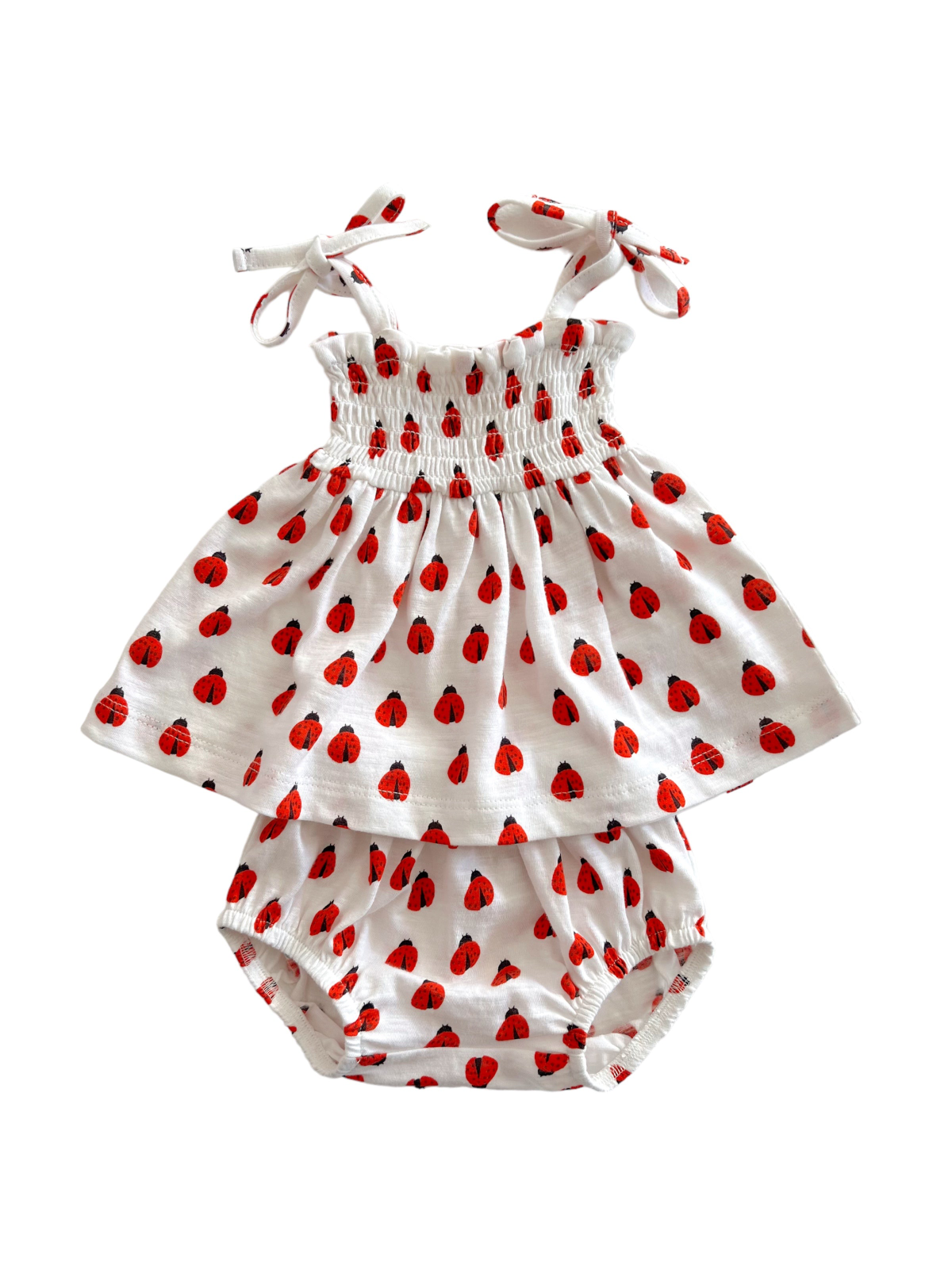 White dress with red ladybug pattern and matching bloomers, featuring adjustable straps and a smocked bodice.