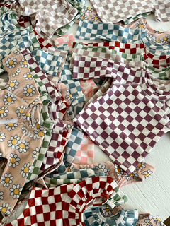Colorful patterned children's shirts in various designs and colors, including checks and daisies, arranged neatly.