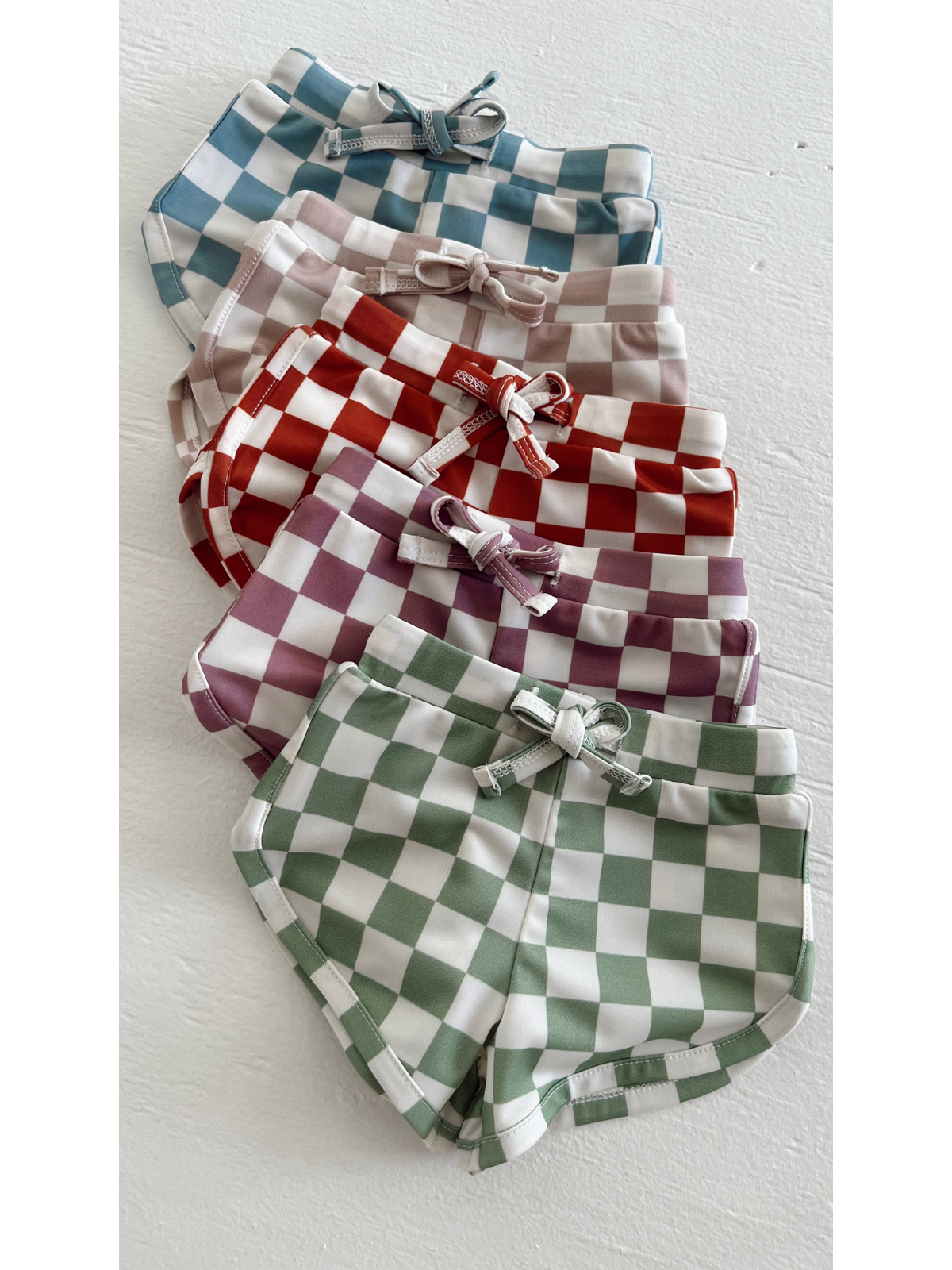 Colorful checkered shorts in various shades, neatly stacked on a white surface.