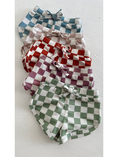 Colorful checkered shorts in various shades, neatly stacked on a white surface.