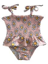 Pink floral swimsuit with smocked bodice and bow straps, featuring white daisies and yellow centers.