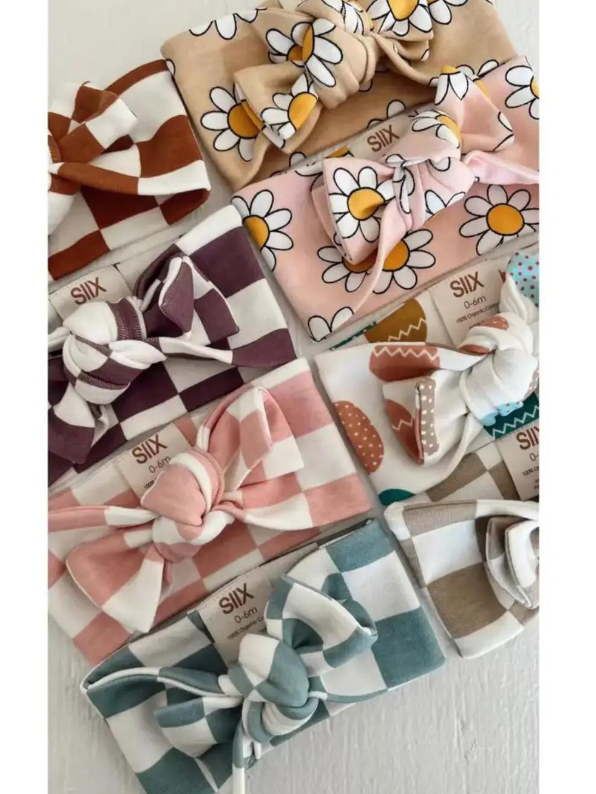 Colorful baby headbands with bows, featuring floral and checkered patterns in various shades.
