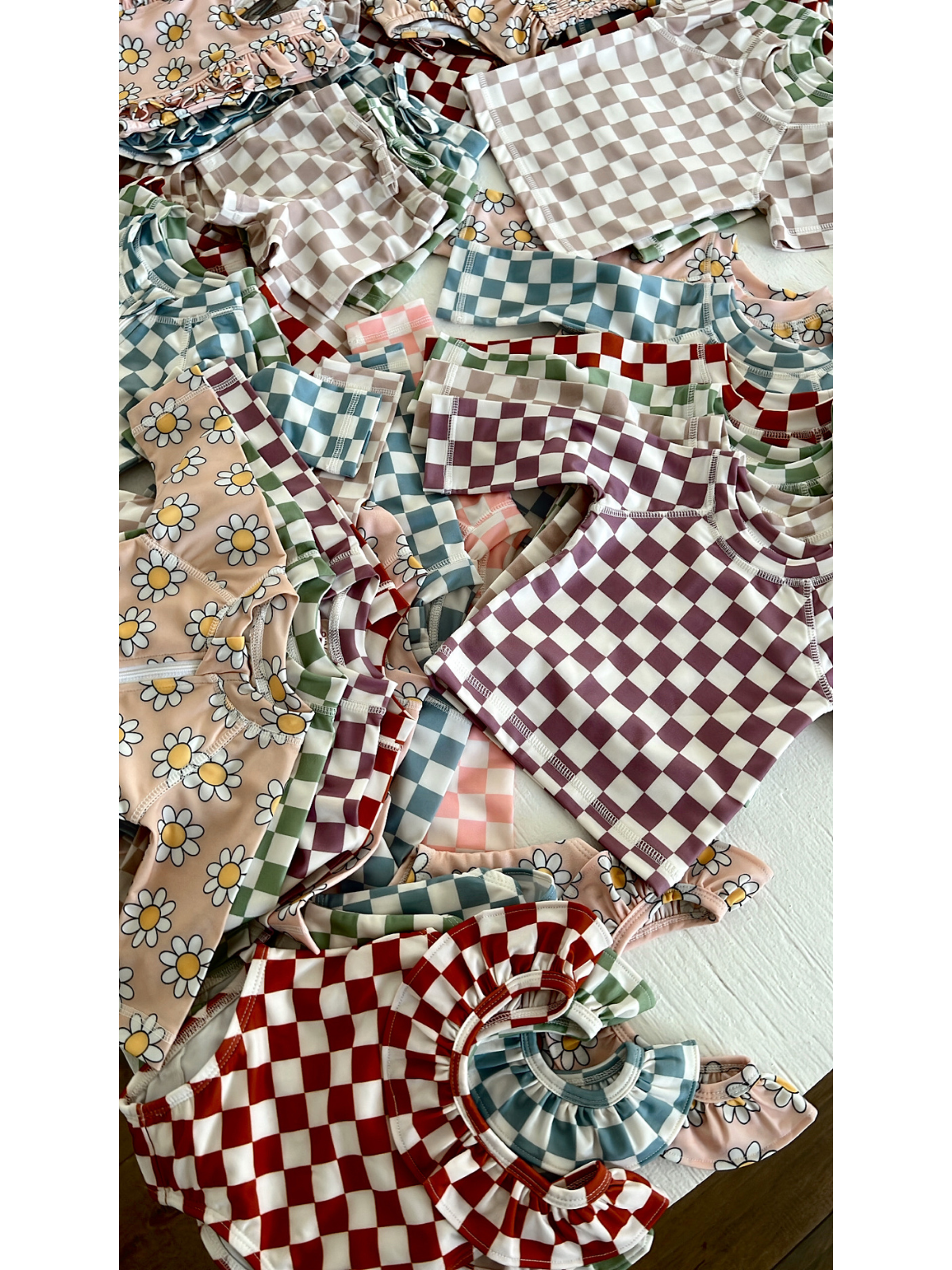 Colorful children's clothing featuring floral and checkered patterns, including tops and blouses stacked together.
