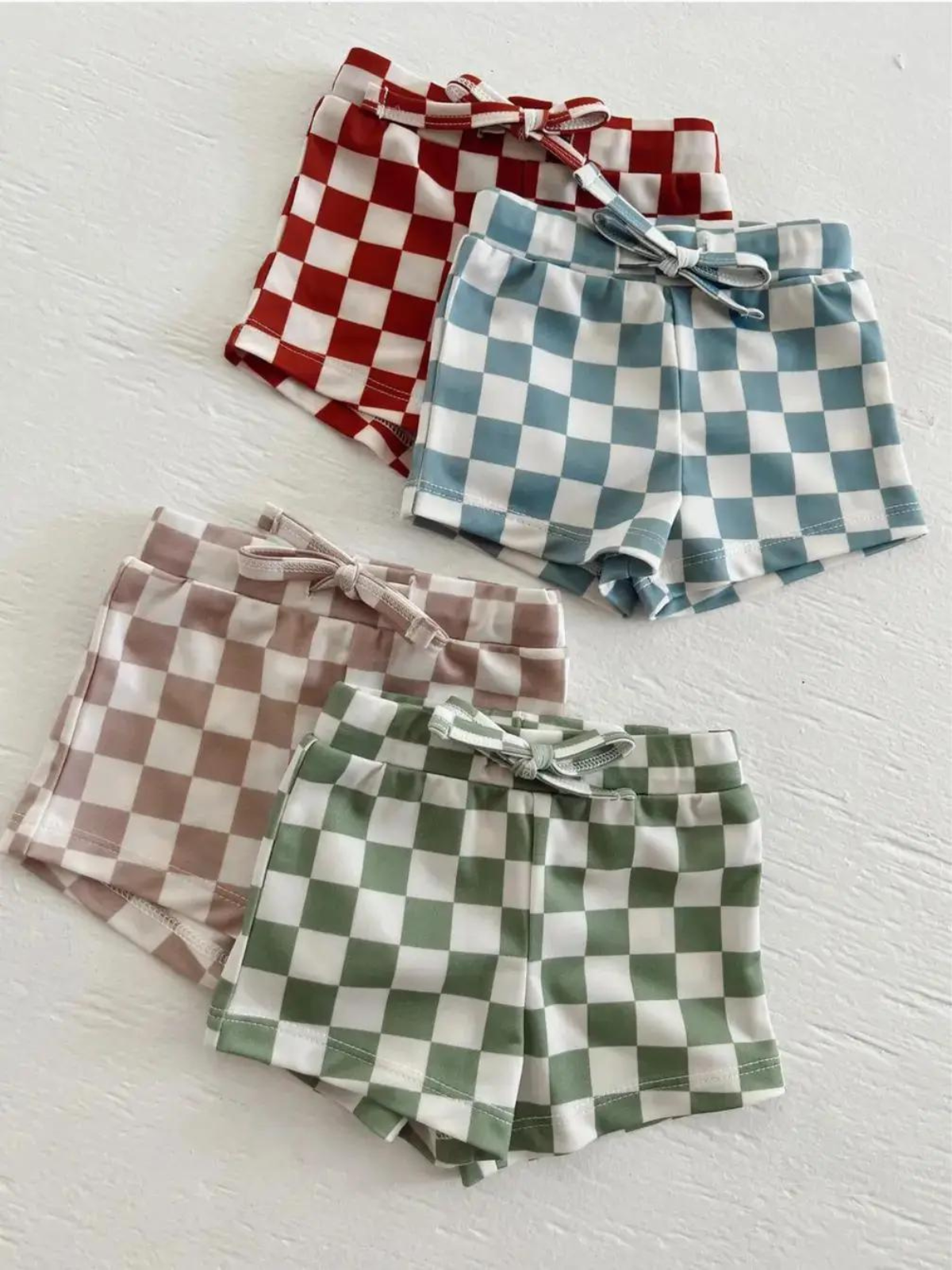 Checkerboard shorts in four colors: red, light blue, pink, and green, each with a matching bow.